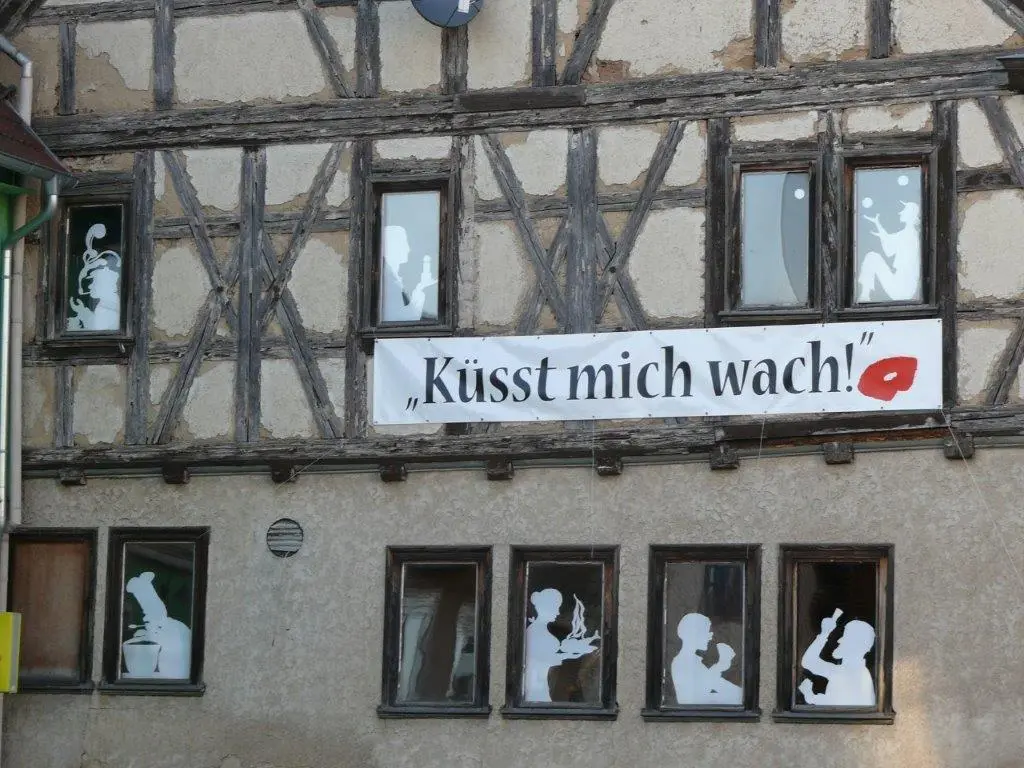 Front eines Fachwerkhausen und Banner mit Aufschrift "Küsst mich wach!"" 